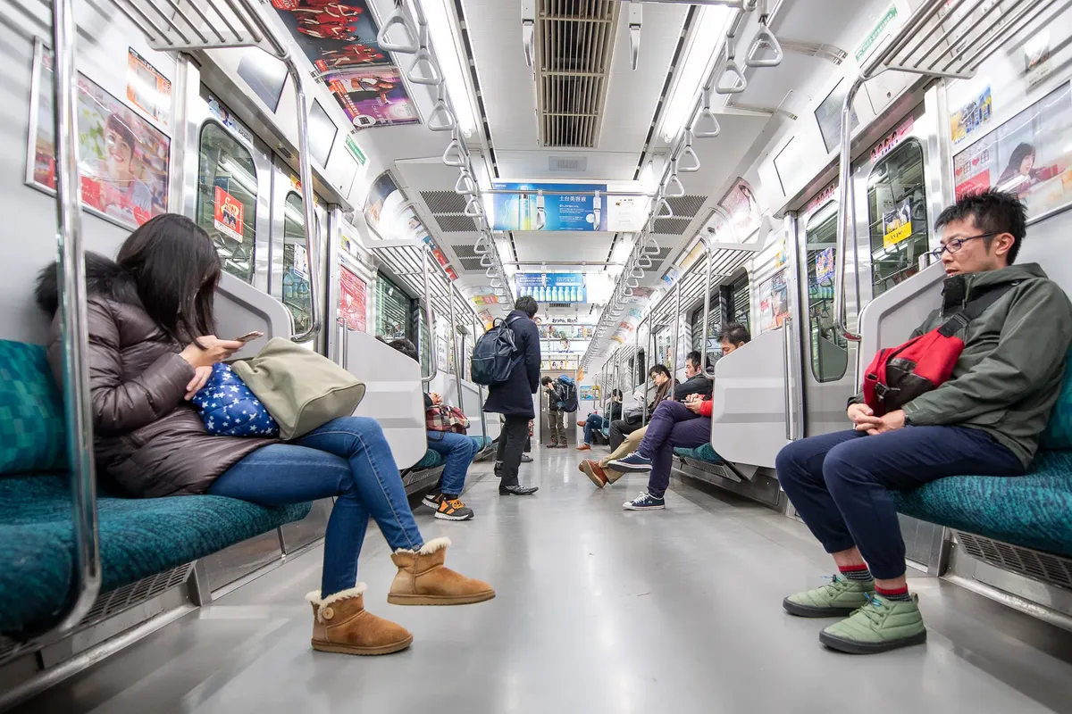 Passengers seated in a Tokyo subway train, showcasing urban lifestyle and winter attire.